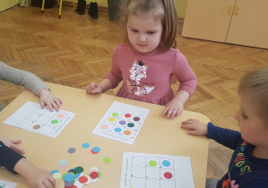 dzieci układają na kratownicy małego formatu kropki zgodnie z kodem kolorystycznym